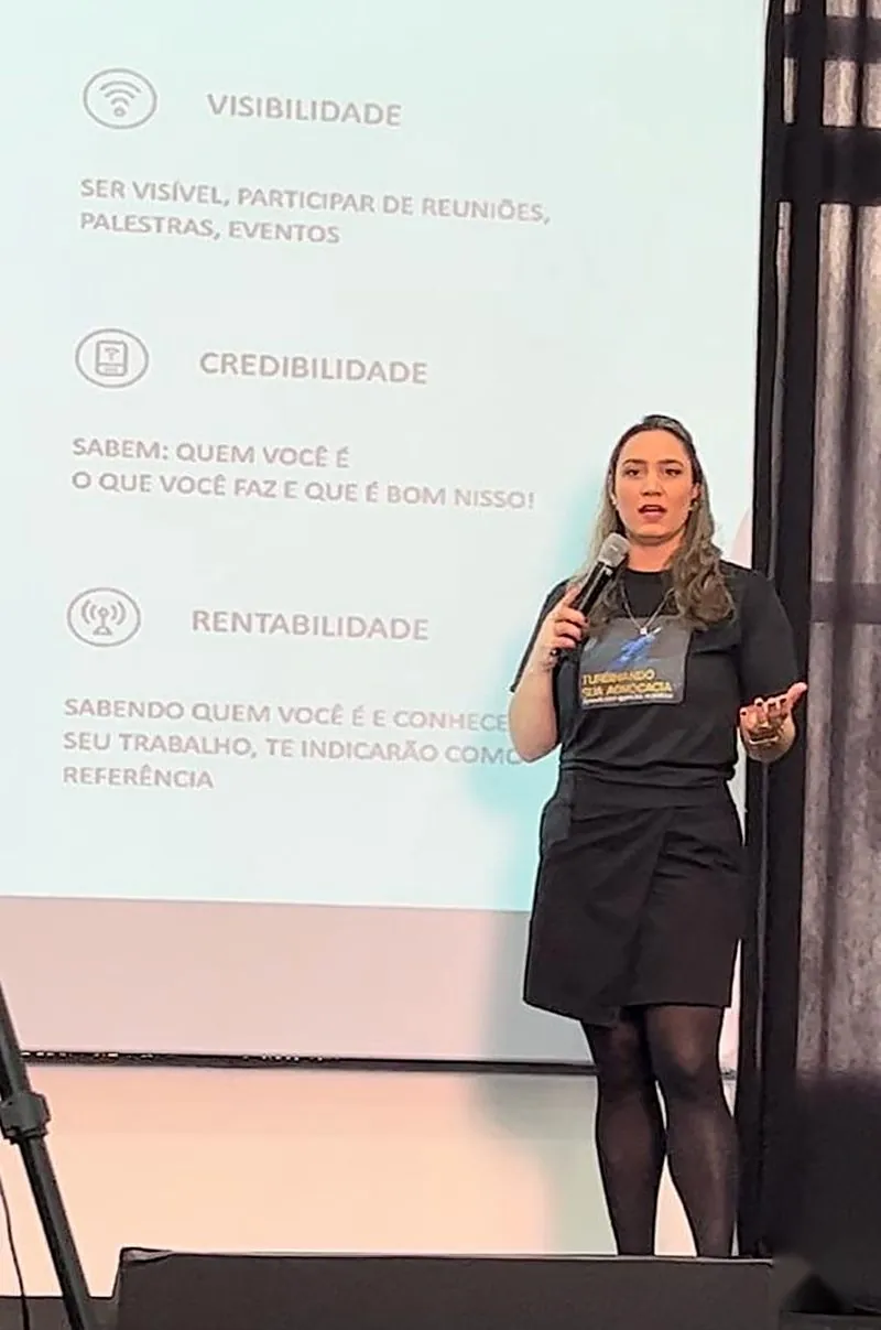 Ellen Acosta palestrando ao lado de slide sobre visibilidade e credibilidade