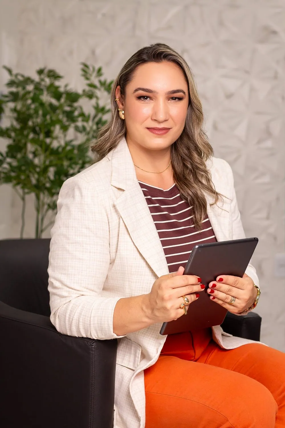 Ellen Acosta sentada em poltrona com tablet